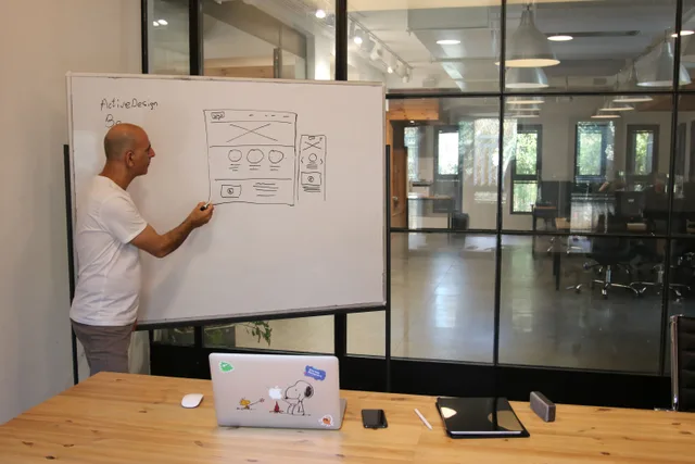 Side view of adult male manager in white t shirt standing near whiteboard and explaining business strategy during work in modern office. Operations case study framework: turn one claim into a two-week trial